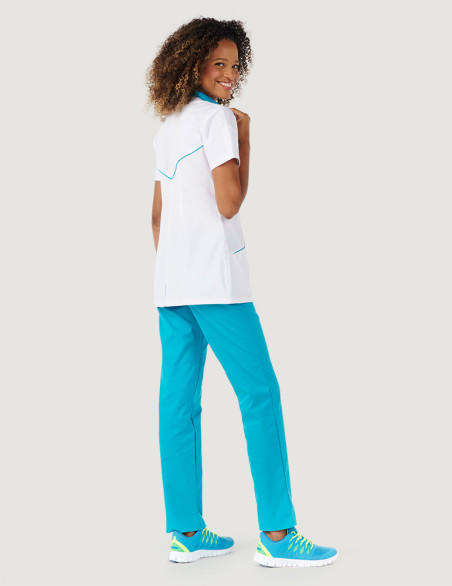 Blouse blanche femme, Mona, avec parements bleu océan Marque Belissa. Vue portée en pied avec pantalon médical bleu océan