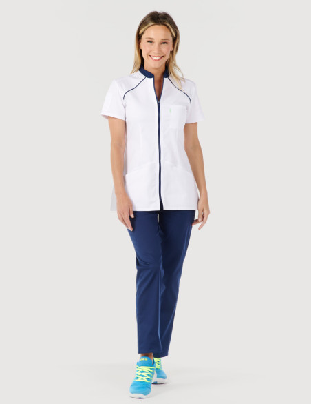 Blouse blanche femme, Mona, avec parements bleu marine Marque Belissa. Vue portée en pied avec pantalon médical marine