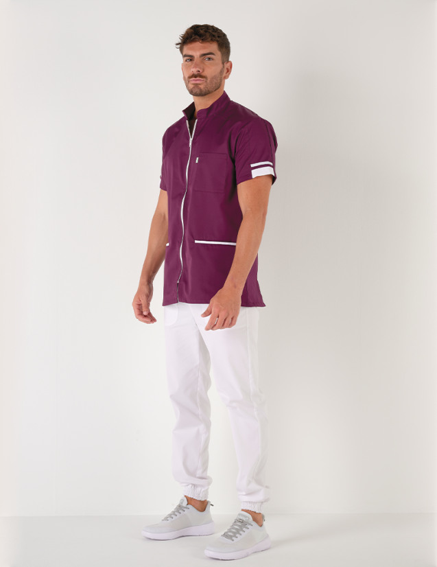 Blouse médicale homme Marley, cassis avec parements blanc. Portée avec un pantalon blanc. Marque Belissa