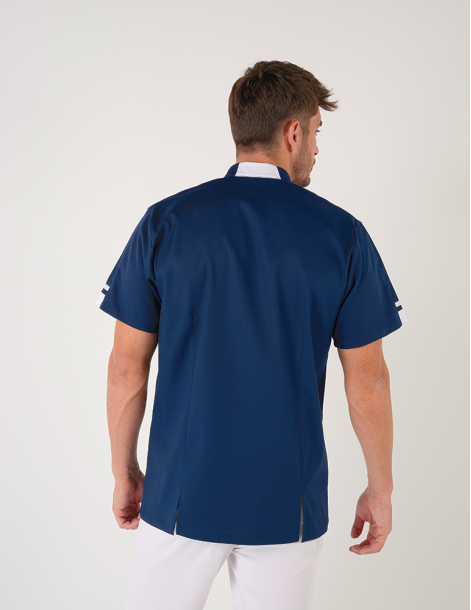 Blouse médicale homme Marley, bleu marine avec parements blanc. Portée avec un pantalon blanc. Marque Belissa 2